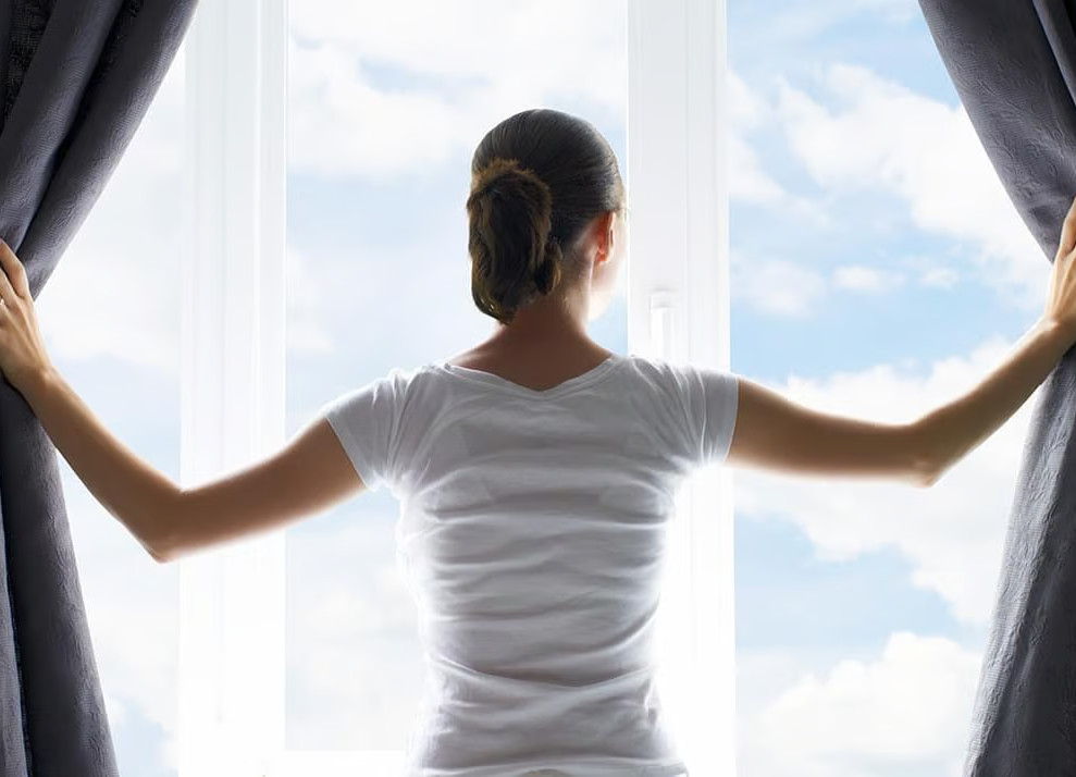 Frau blickt aus Fenster mit termochromem Glas